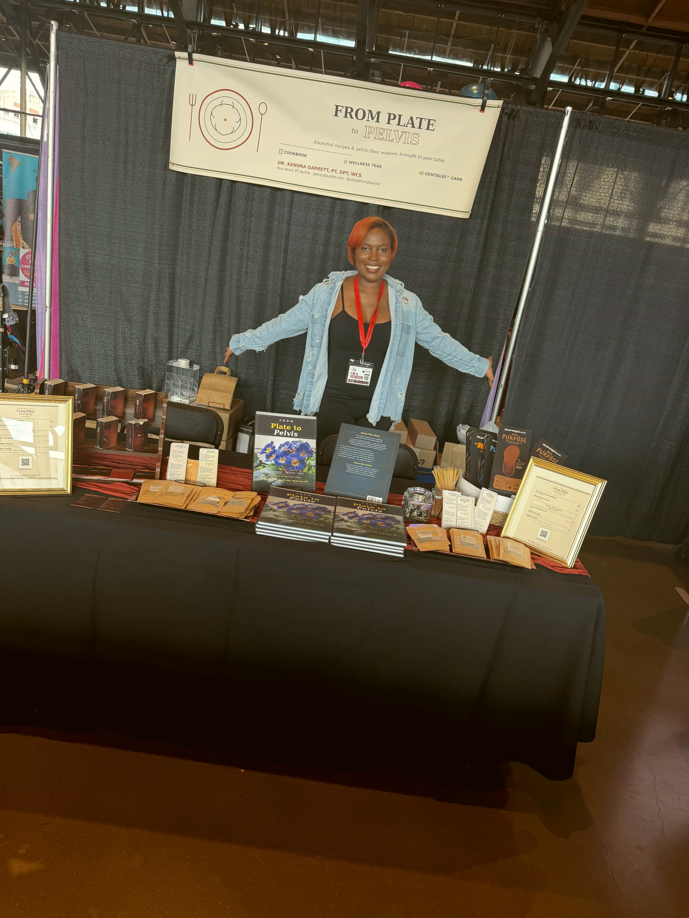 Dr. Kendra Garrett standing behind the From Plate to Pelvis booth at the Virginia Black Expo